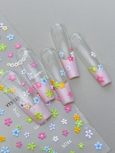 Macro detail of 3D embossed colorful flower nail stickers with spring text on fake nails