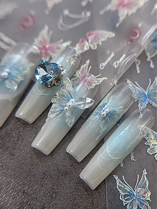 Macro shot of 3D aurora butterfly charms and heart rhinestones on coffin press-on nails