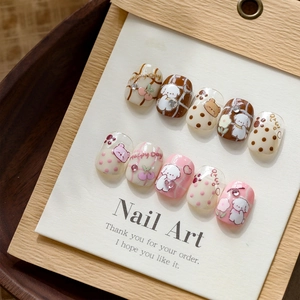 Detail of pink and brown 3D embossed press-on nails with cute puppy and cherry motifs