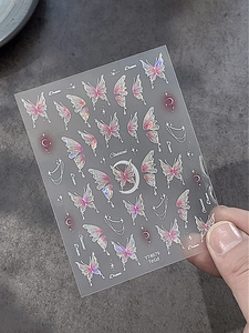 Detailed view of iridescent butterfly and moon nail art stickers with metallic holographic finish