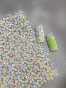 Detail of holographic flower nail stickers with 3D shell shimmer and butterfly bow accents