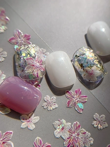 Macro detail of cherry blossom press-on nails with purple cat-eye and glitter finish