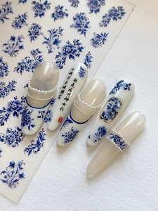 Detail of blue and white porcelain nail art with floral patterns and pearl accents