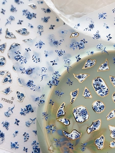 Macro detail of embossed blue and white porcelain nail stickers with gold edge accents