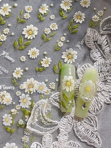 Close-up of 3D daisy nail stickers with floral patterns on elegant green nails