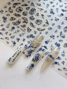 Detail of blue white floral nail stickers with gold accents and Chinese art patterns
