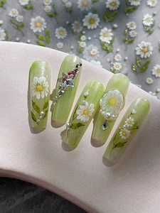 Close-up of green daisy nail art with 3D rhinestones and pearls on display stand