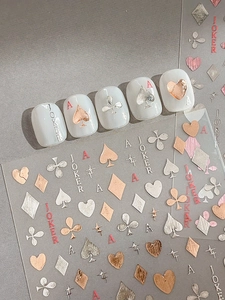 Macro view of metallic embossed poker nail stickers with hearts and spade patterns