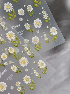 Macro shot of 3D embossed daisy nail art stickers showing detailed floral patterns