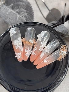 Dettaglio macro di unghie sfumate con fiori 3D, perle e dettagli in filo metallico oro rosa