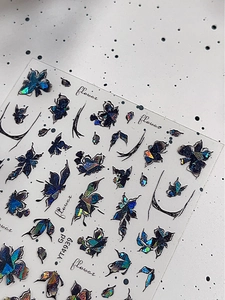 Vista macro di adesivi per unghie iridescenti con fiori e farfalle in rilievo 3D