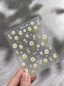 Detailed macro view of 5D white daisy embossed nail art stickers with textured floral patterns