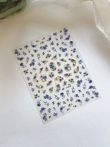 Macro detail of blue and white porcelain nail stickers with elegant gold trim edges