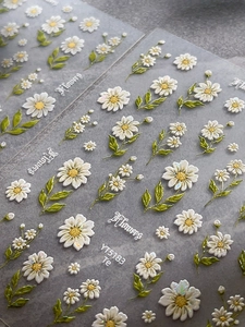 Macro shot of 3D embossed daisy nail stickers with glitter accents and floral patterns