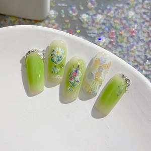 Green and cream gradient nail art tips with hand-painted flower and butterfly accents
