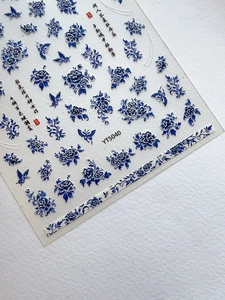 Detailed macro shot of blue and white porcelain nail stickers with floral and butterfly patterns