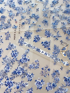 Macro detail of blue porcelain nail art stickers with peony flower patterns and calligraphy