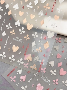Detailed view of silver and rose gold poker nail stickers with heart and spade patterns