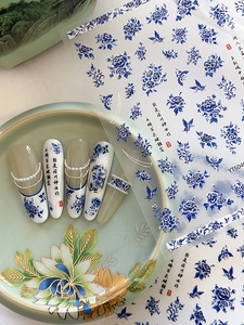 Close-up of blue and white porcelain nail art stickers with classic floral and butterfly patterns