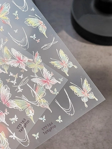 Detailed macro view of holographic butterfly nail art stickers with iridescent patterns