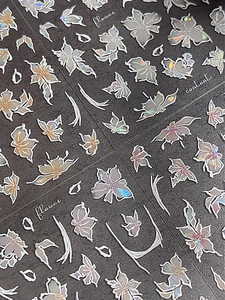 Dettaglio di adesivi per unghie floreali con finitura laser e motivi di fiori bianchi