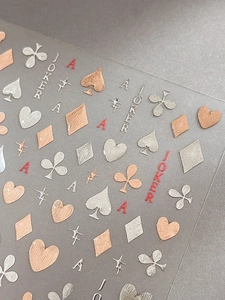 Macro view of 3D rose gold poker themed nail art stickers with metallic embossed texture
