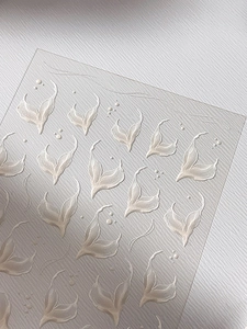 Dettaglio di adesivi 3D per unghie a rilievo con trama a petali bianco perlato