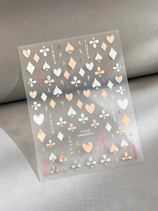 Macro view of embossed poker nail art stickers with gold, white, and red motifs