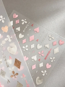 Detail of embossed rose gold poker nail decals featuring heart and joker patterns