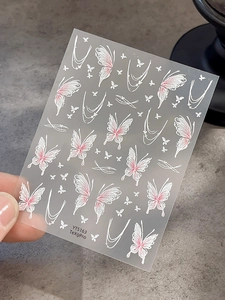 Macro shot of 3D butterfly nail art stickers with pink gradient and white outlines