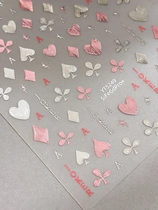 Macro shot of 3D rose gold poker themed nail stickers with hearts and spades