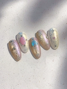 Dettaglio di unghie finte con sfumature rosa, glitter e decorazioni a forma di cuore