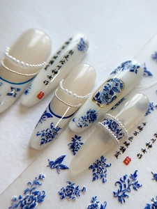Macro view of blue porcelain style press-on nails with floral motifs and pearl chains