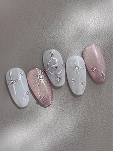 Dettaglio unghie rosa cat-eye con stelle argentate e decorazioni in strass brillanti