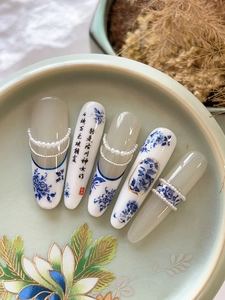 Detailed macro view of Chinese style blue and white porcelain nail art with pearl chains