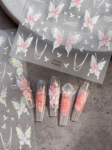 Close-up of pink butterfly nail stickers on long transparent acrylic nails with sparkles