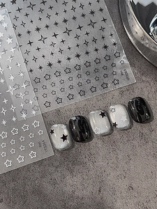 Gros plan d'autocollants pour ongles étoiles noires et blanches avec effet sur ongle