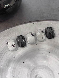 Vue macro d'autocollants pour ongles étoiles noires et argentées sur un plat en céramique