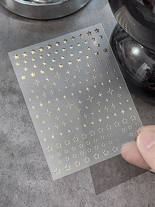 Gros plan d'autocollants pour ongles étoiles dorées avec divers motifs sur support clair