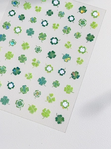 Gros plan de stickers à ongles trèfles verts avec paillettes sur cuir crème