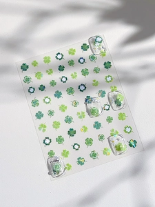 Gros plan d'autocollants pour ongles trèfles verts et marguerites avec paillettes