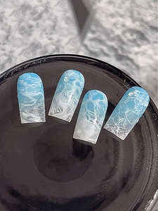 Vue macro d'ongles adhésifs à motif marbré bleu avec gouttes d'eau 3D sur fond noir