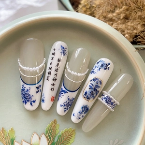 Blue and white porcelain style press-on nails with pearls and calligraphy art in a tray