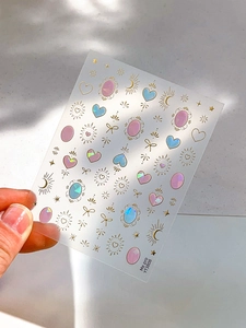 Dettaglio di adesivi olografici per unghie con cuori dorati, stelle e fiocchetti