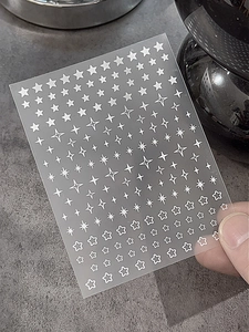 Gros plan de stickers à ongles étoiles blanches aux formes variées pour manucure créative