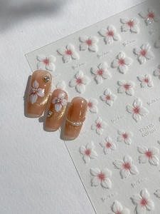Detailed macro view of 3D cherry blossom nail stickers with pearls and metallic beads