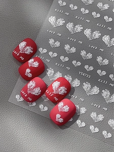 Detailansicht der 3D-Prägung roter Herz-Nagelaufkleber und Schriftzug auf matten Tips