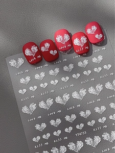 Nahaufnahme von 3D-geprägten weißen Herz-Nagelstickern mit LOVE ME Schriftzug auf Rot