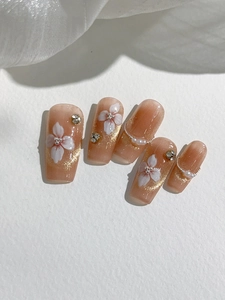 Macro view of nude pink gradient press-on nails with white flower and pearl details