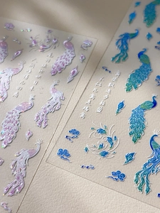 Detailed macro view of laser-cut peacock nail stickers with Chinese calligraphy text